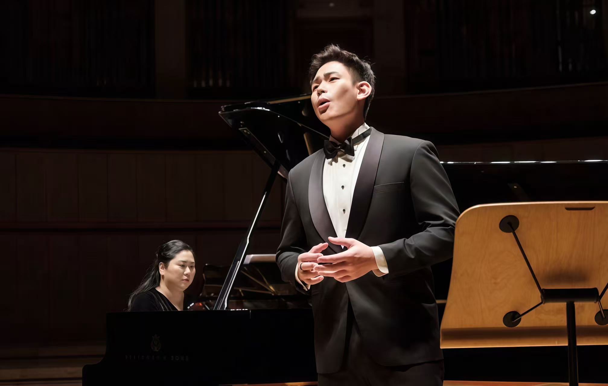 Alvin in concert dress, mid-aria, on stage with grand piano accompanist