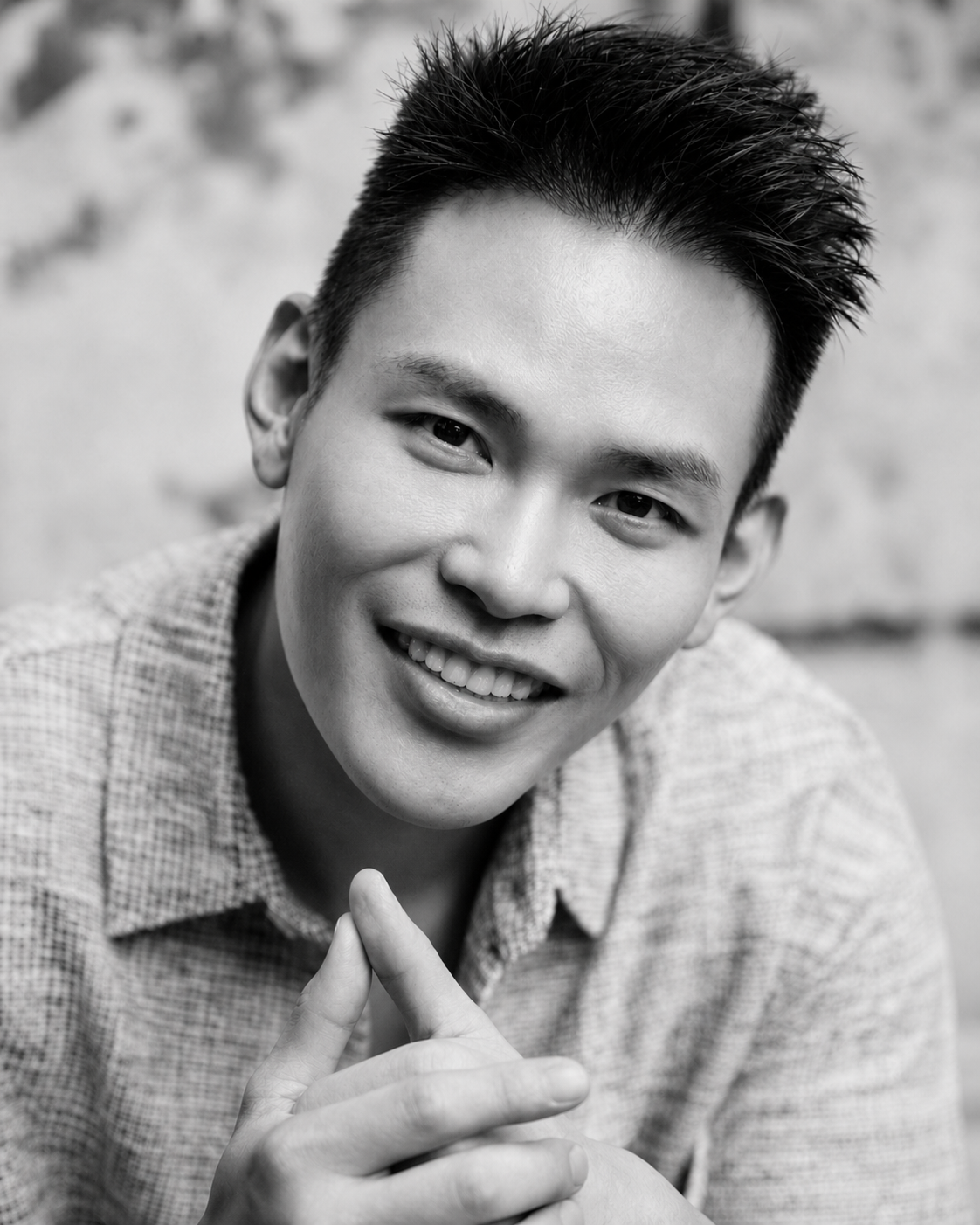 Black-and-white portrait. Alvin smiling with hands clasped near face