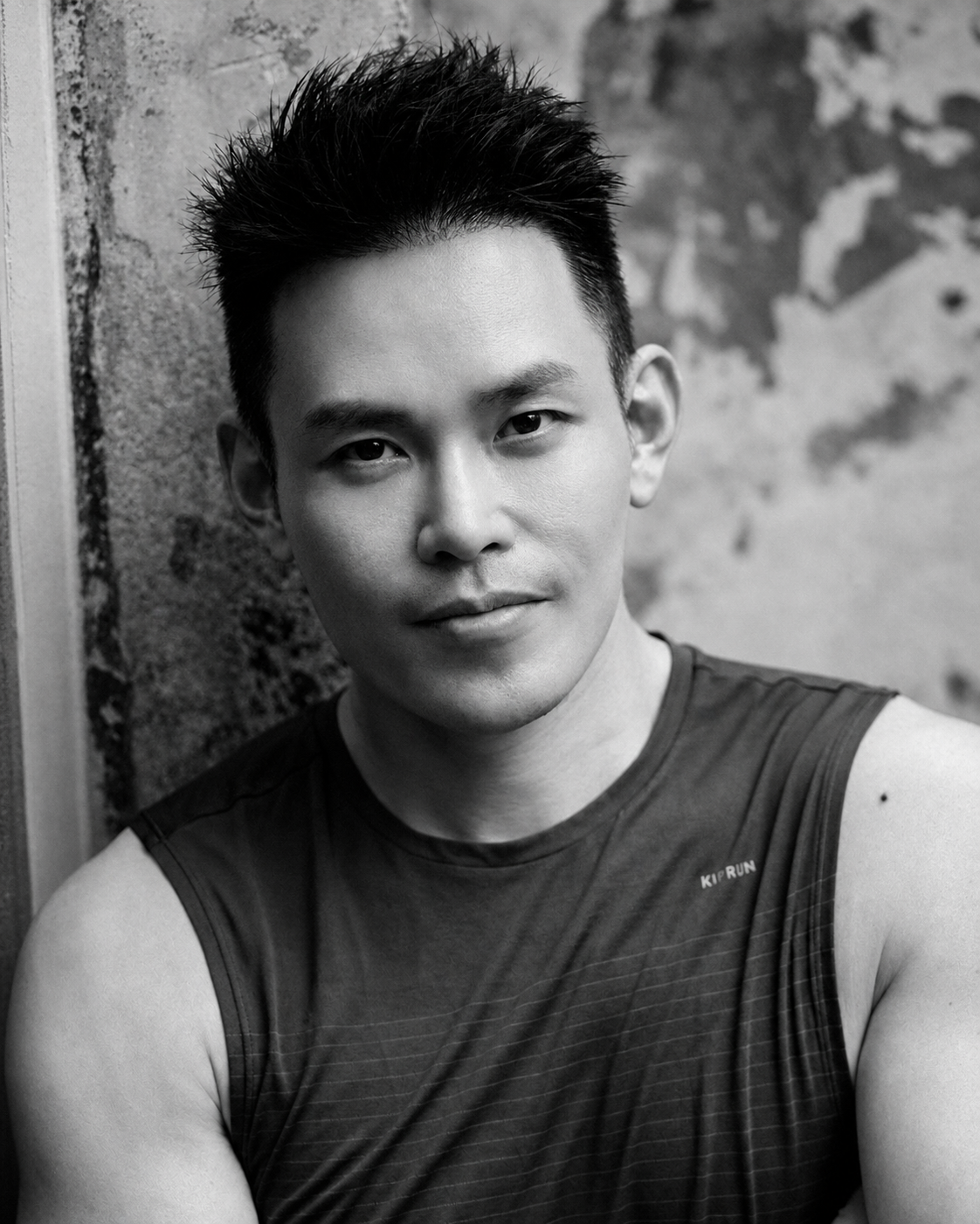 Black-and-white studio portrait. Alvin in athletic top against a textured wall