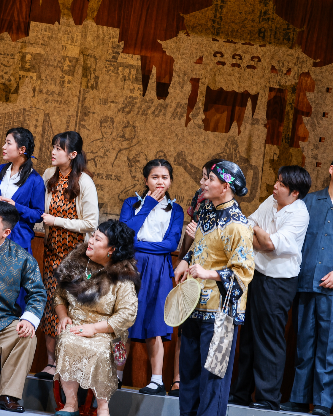 Alvin in mustard-gold embroidered matchmaker's robe with fan and bag, surrounded by chorus members in 1960s Hong Kong dress
